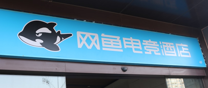 A building entrance features a vibrant blue sign with white Chinese characters and a stylized orca logo in black and white. The overall appearance suggests an establishment focused on eSports or digital activities.
